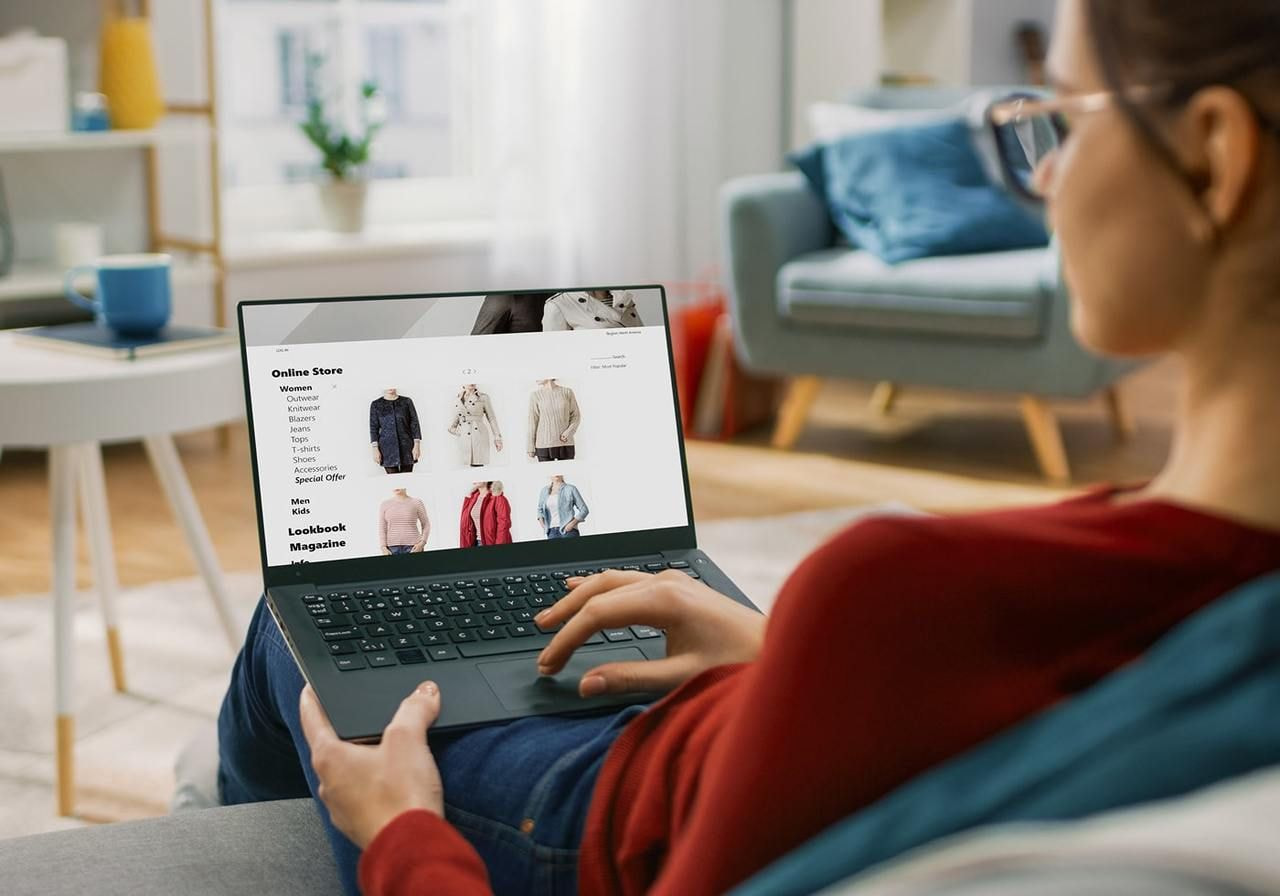 A woman is scrolling through an online store using a laptop.